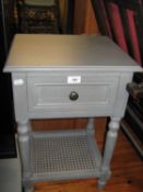 A GREY PAINTED WOOD BEDSIDE PEDESTAL WITH DRAWER AND CANE PANEL UNDERSHELF AND A BLOND WOOD SINGLE