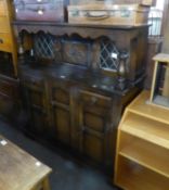 AN OAK COURT CUPBOARD, THE CANOPY TOP HAVING TWO LEAD LIGHT DOORS AND A CENTRE PANEL DOOR, THE