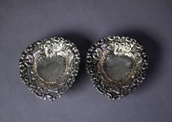PAIR OF SILVER PIERCED AND REPOUSSÉ HEART SHAPED SWEET MEAT DISHES, each on three ball feet, 3 ½? (