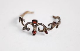 STERLING SILVER BOLD SCROLL PATTERN TORQUE BANGLE, collet set with six variously shaped garnets