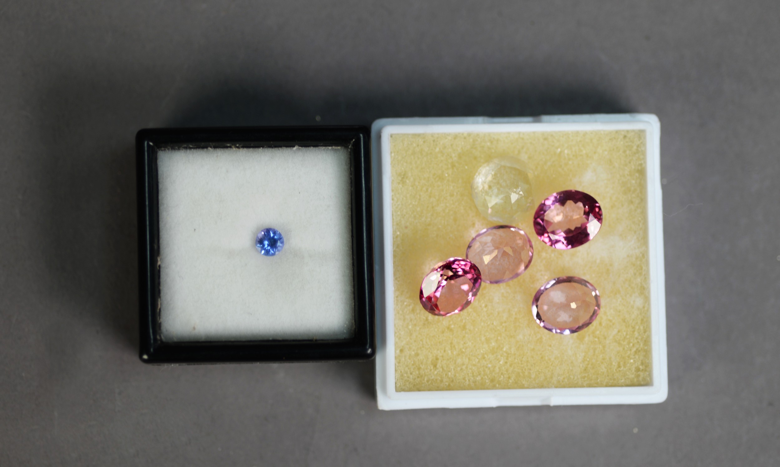 White plastic vision box containing FOUR UNMOUNTED PINK GEM STONES and ONE WHITE OVAL GEM STONE