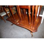 A MAHOGANY LARGE OBLONG COFFEE TABLE WITH SERPENTINE OUTLINE, ON QUARTETTE SUPPORTS WITH BRASS