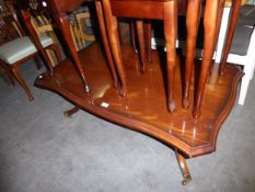 A MAHOGANY LARGE OBLONG COFFEE TABLE WITH SERPENTINE OUTLINE, ON QUARTETTE SUPPORTS WITH BRASS