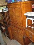 A REPRODUCTION WALNUTWOOD COCKTAIL CABINET, THE UPPER SECTION HAVING GLASS SHELVES, BEHIND TWO PANEL