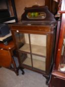 AN OAK DISPLAY CABINET, ENCLOSED BY A GLAZED FOUR PANEL DOOR, ON CABRIOLE SUPPORTS, THE LOWER RAISED