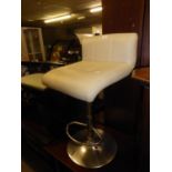 A CREAM HIDE LOW BACKED CHAIR, REVOLVING ON A BRIGHT METAL BASE WITH CIRCULAR FOOT