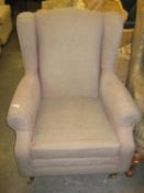 A FIRESIDE ARMCHAIR COVERED IN LIGHT BROWN/BEIGE FABRIC