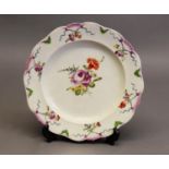 18th CENTURY GERMAN LUDWIGSBURG HARD-PASTE PORCELAIN PLATE, the scalloped rim accentuated in purple,