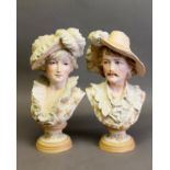 PAIR OF TINTED BISQUE BUSTS, heightened in gilt, each modelled with feathered hat and raised on a