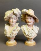 PAIR OF TINTED BISQUE BUSTS, heightened in gilt, each modelled with feathered hat and raised on a