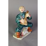 GOLDSCHEIDER WITH MYOTTS POTTERY COMICAL COSSACK SEATED FIGURE, playing the balalaika, in green