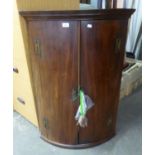 A MAHOGANY ANTIQUE BOW FRONTED CORNER CABINET, WITH 'H' HINGES (LACKING ONE SHELF) 106cm high