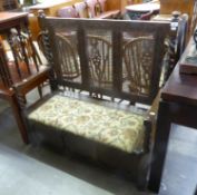 EARLY TWENTIETH CENTURY CARVED OAK MONK’S BENCH OR BOX SETTLE, with three panelled caned back,