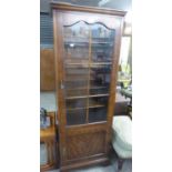 A TALL NARROW MAHOGANY BOOKCASE BY CAMEO FURNITURE, HAVING A SIX PANEL GLAZED DOOR OVER A SMALL