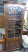 A TALL NARROW MAHOGANY BOOKCASE BY CAMEO FURNITURE, HAVING A SIX PANEL GLAZED DOOR OVER A SMALL