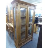 A LARGE PINE TWO DOOR GLAZED BOOKCASE WITH SINGLE DRAWER ON BUN FEET