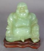 MODERN ORIENTAL JADE COLOURED CARVED HARDSTONE FIGURE OF HOTEI, modelled seated, 3 ¾” (9.5m) high,