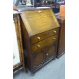 SMALL OAK BUREAU, with two doors over a pair of cupboard doors, on bun feet, 106cm high