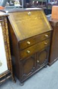 SMALL OAK BUREAU, with two doors over a pair of cupboard doors, on bun feet, 106cm high