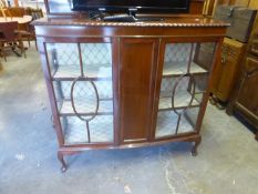 A MAHOGANY BOW FRONTED DISPLAY CABINET WITH LEDGE BACK, TWO GLAZED DOORS FLANKING A CENTRE PANEL,
