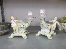 PAIR OF CONTINENTAL PORCELAIN FIGURAL BON BON DISHES WITH CANDLE HOLDERS IN THE ROCOCO TASTE, 7 ¼”