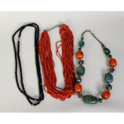 TWENTY-STRAND NECKLACE OF RED CORAL MICRO-BEADS; NECKLACE OF UNIFORM FACETED JET BEADS,