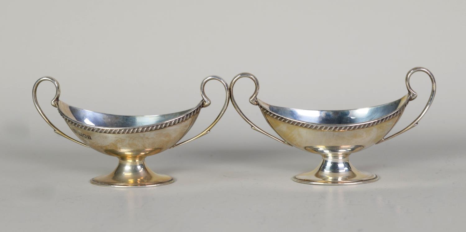 EDWARD VII PAIR OF SILVER TWO HANDLED OPEN SALTS, each of boat shaped pedestal urn form with high
