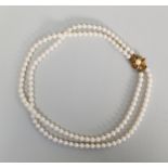 TWO-STRAIND NECKLACE OF UNIFORM CULTURED PEARLS with 9ct gold flower pattern clip se with a pearl,
