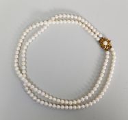 TWO-STRAIND NECKLACE OF UNIFORM CULTURED PEARLS with 9ct gold flower pattern clip se with a pearl,