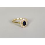 18ct GOLD, SAPPHIRE AND DIAMOND CLUSTER RING, with collet set centre oval dark blue sapphire and