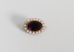 GOLD COLOURED METAL BROOCH collet set with an oval amethyst and surround of seed pearls, 1in (2.5cm)