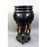 ORIENTAL CARVED AND EBONISED WOOD URN STAND, raised on three bulky elephant head supports to a