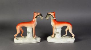 PAIR OF LATE NINETEENTH CENTURY STAFFORDSHIRE POTTERY FIGURES OF STANDING GREYHOUNDS, dead game in
