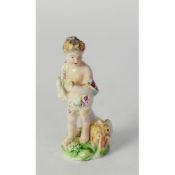 18th CENTURU DERBY CHINA FIGURE OF A PUTTO HOLDING A CORNUCOPIA, on natural green and floral and