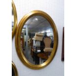 AN OVAL WALL MIRROR, IN STEP MOULDED GILT FRAME