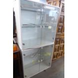 A WHITE ENAMELLED WOOD TWO TIER STACKING DISPLAY CABINET WITH HINGED PLATE GLASS DOORS AND A PLATE
