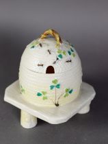 BELLEEK EARLY TWENTIETH CENTURY HONEY SKEEP AND COVER, SHAMROCK AND BEES, PATTERN raised on a rustic