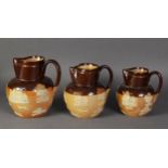 GRADUATED SET OF THREE ROYAL DOULTON SALT GLAZED STONEWARE JUG, sprigged with toping scenes, 6”,