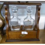 AN OAK TWO DIVISION TANTALUS FRAME WITH TWO ITALIAN ‘RCR PRIMAVERA’ PLAIN GLASS SPIRIT DECANTERS
