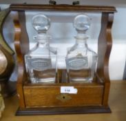 AN OAK TWO DIVISION TANTALUS FRAME WITH TWO ITALIAN ‘RCR PRIMAVERA’ PLAIN GLASS SPIRIT DECANTERS