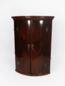 GEORGE III FIGURED MAHOGANY BOW FRONTED CORNER CUPBOARD, of typical form with four spice drawers and