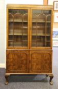 EARLY TWENTIETH CENTURY FIGURED WALNUT DISPLAY CABINET, the moulded oblong top above a pair of