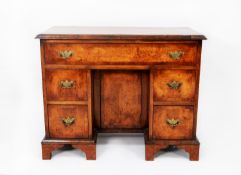 TWENTIETH CENTURY GEORGE II STYLE FIGURED WALNUT AND CROSSBANDED KNEEHOLE DESK, the moulded oblong