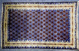 EASTERN RUG with all-over pattern of rows of dark red/brown small diamond shapes on a dark blue