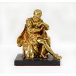 EARLY 20th CENTURY GILT BRASS FIGURE OF AN ELIZABETHAN GENTLEMAN SEATED ON A STOOL, possibly