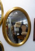 AN OVAL WALL MIRROR, IN STEP MOULDED GILT FRAME