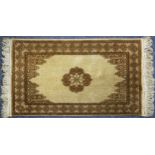 EASTERN RUG with light brown small centre floral medallion on a plain fawn field with shaped