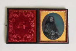 VICTORIAN COLOUR TINTED AMBROTYPE PHOTOGRAPH OF A SEATED LADY, in black costume in the embossed