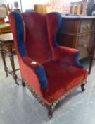 A LATE VICTORIAN MAHOGANY FRAMED WINGED BACK ARMCHAIR, COVERED IN RED AND BLUE FABRIC