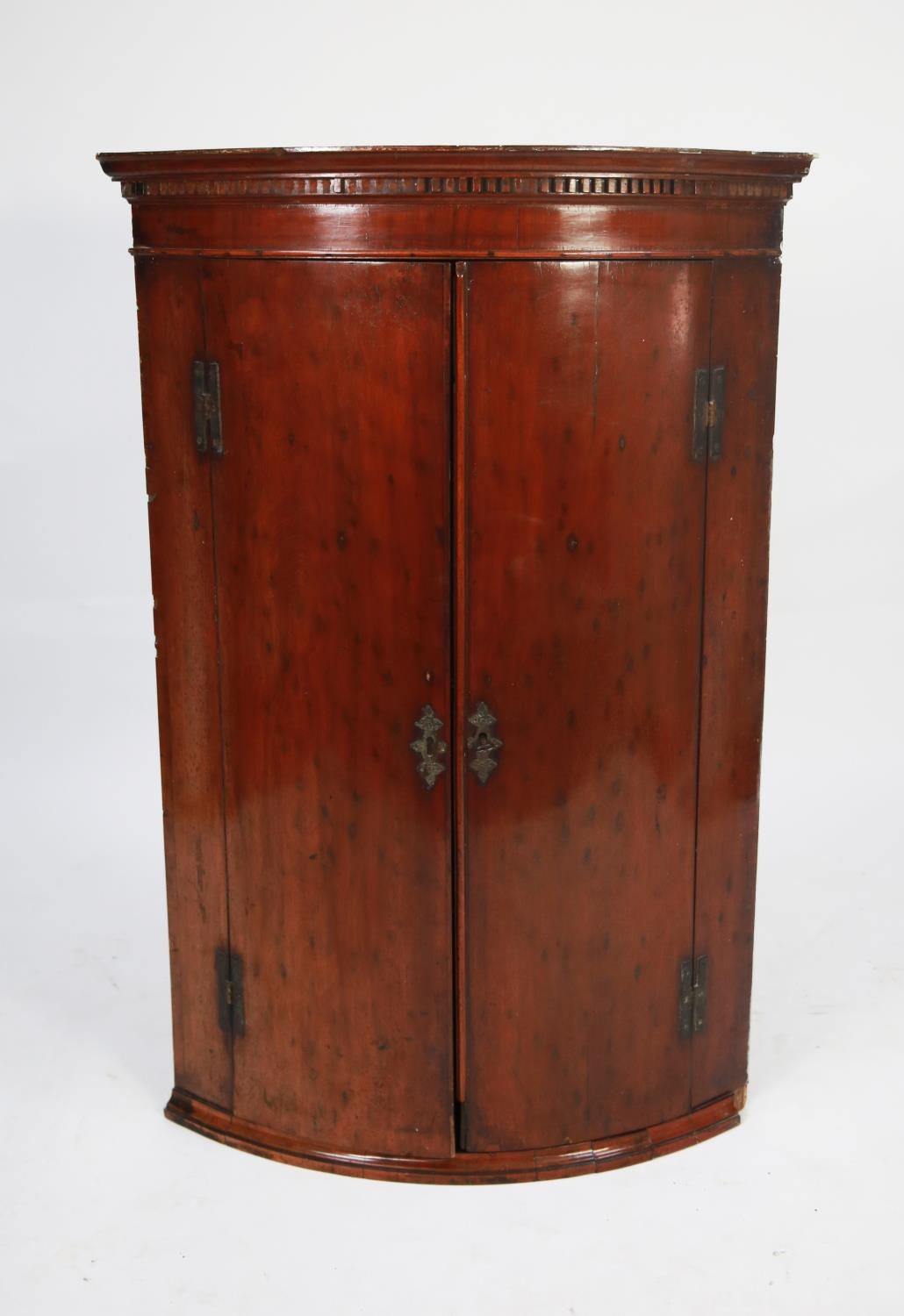 GEORGE III ’PLUM PUDDING’ MAHOGANY BOW FRONTED CORNER CUPBOARD, of typical form with dentil